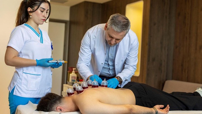 Dr. Erdal Dilekci, a specialist in physical medicine and rehabilitation at Medicana International Hospital, performs cupping therapy on Furkan Ali Sayan in Istanbul, Turkey, August 28, 2025. Known locally as hacamat, wet cupping and other traditional treatments such as leech therapy are being increasingly performed under government oversight in Turkey, rather than in informal settings such as homes, to complement modern medicine and cut down infection risks. REUTERS/Umit Bektas