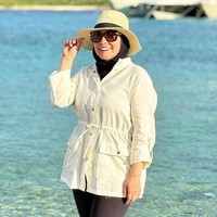 Wanita 45 tahun ini tampil effortless chic dengan outer beige beraksen ikat pinggang, dipadu legging hitam dan hijab hitam. Topi jerami dan kacamata hitam menjadikan look bernuansa liburan musim panas. Foto: Instagram/@astridkuya