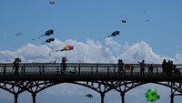 Pengunjung menyaksikan layang-layang beraneka bentuk menghiasi langit pada pembukaan Festival Layang-Layang St Anne, Inggris. Foto: REUTERS/Phil Noble