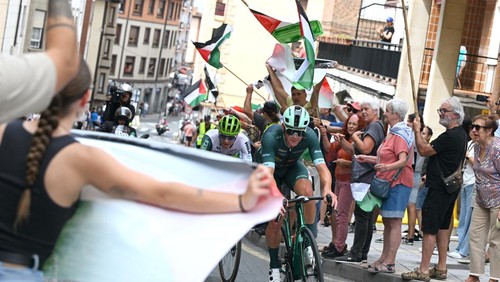 BILBAO, SPAIN - SEPTEMBER 03: (L-R) Joel Nicolau of Spain and Team Caja Rural - Seguros RGA and Mads Pedersen of Denmark and Team Lidl - Trek - Green Points Jersey compete in the breakaway while a group of fans protest displaying Palestinian flags during the La Vuelta - 80th Tour of Spain 2025, Stage 11 a 157.4km stage from Bilbao to Bilbao / #UCIWT / on September 03, 2025 in Bilbao, Spain. (Photo by Dario Belingheri/Getty Images)