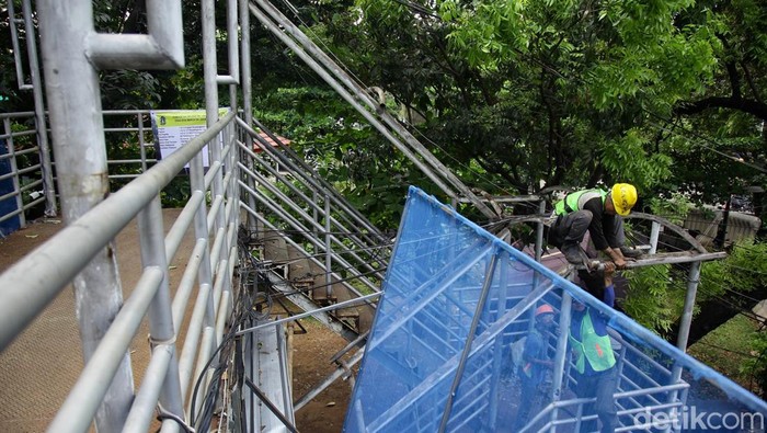 Pemprov Jakarta Kebut Perbaikan JPO, Target Rampung Akhir 2025 Pekerja mempersiapkan material saat perbaikan atap JPO di Jl Medan Merdeka Barat, Jakarta, Kamis (4/9/2025).