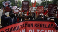 Barisan peserta aksi membawa sederet poster tuntutan dan mengibarkan bendera organisasi buruh sebagai simbol solidaritas perjuangan rakyat di tengah demonstrasi damai.