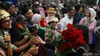 Peserta aksi membagikan bunga mawar merah sebagai simbol damai dan cinta.