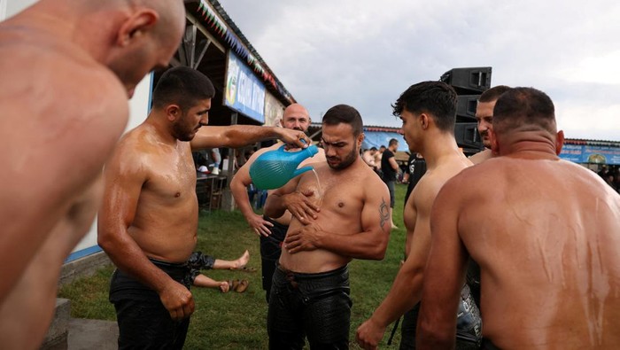 Gulat Minyak Spektakuler Hidupkan Tradisi Ottoman di Bulgaria Wrestlers covered in oil prepare before a traditional oil wrestling competition in the village of Cherna, Bulgaria, August 31, 2025. REUTERS/Stoyan Nenov