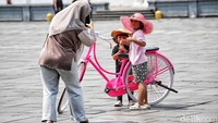 Anak-anak berpose dengan topi lebar dan kacamata unik, menjadikan sepeda ontel bukan hanya alat transportasi, tetapi juga gaya berfoto.