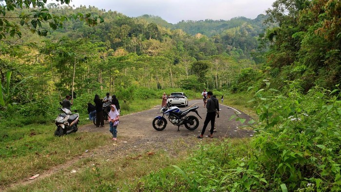 Sejumlah warga berada di ujung jalan Jalur Lintas Selatan (JLS) di Kendenglembu, Banyuwangi, Jawa Timur, Jumat (5/9/2025). Proyek Strategis Nasional yang menghubungkan Banyuwangi dan Jember tersebut memiliki panjang total 99,18 kilometer, dengan 68,08 kilometer sudah rampung dan 14,1 kilometer sisanya tertunda akibat proses pembebasan lahan di area perkebunan yang harus mematuhi UU pertanahan dan Peraturan Menteri LHK. ANTARA FOTO/Budi Candra Setya/nz