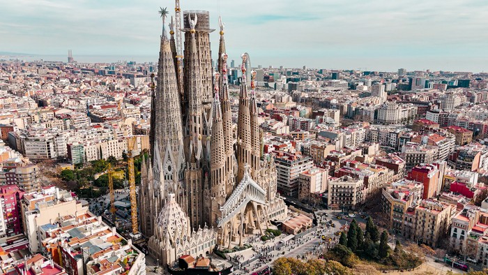 Aerial view of Sagrada Familia Cathedral in Barcelona, Catalonia, Spain, Aerial view of Barcelona Eixample residential area and Sagrada Familia Basilica, most famous travel destinations in europe

The Basílica i Temple Expiatori de la Sagrada Família, otherwise known as Sagrada Família, is a church under construction in the Eixample district of Barcelona, Catalonia, Spain. It is the largest unfinished Catholic church in the world. Designed by Catalan architect Antoni Gaudí (1852–1926), his work on Sagrada Família is part of a UNESCO World Heritage Site. On 7 November 2010, Pope Benedict XVI consecrated the church and proclaimed it a minor basilica.
On 19 March 1882, construction of the Sagrada Família began under architect Francisco de Paula del Villar. In 1883, when Villar resigned, Gaudí took over as chief architect, transforming the project with his architectural and engineering style, combining Gothic and curvilinear Art Nouveau forms. Gaudí devoted the remainder of his life to the project, and he is buried in the churchs crypt. At the time of his death in 1926, less than a quarter of the project was complete.