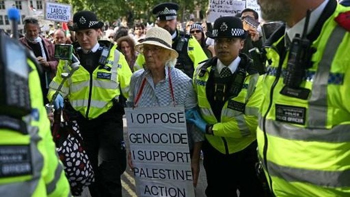 An elderly protester is taken away by police officers at a 