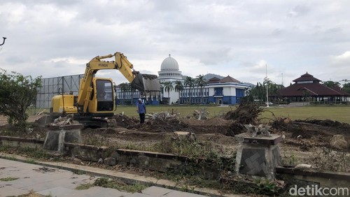 Alat berat sedang mencabut sisa akar pohon di depan Gedung Bupati Lombok Barat untuk pembangunan alun-alun, Senin (8/9/2025). (M. Zahiruddin/detikBali)