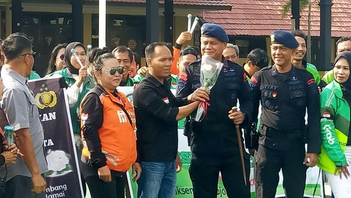 Pengemudi ojol memberikan bunga mawar ke aparat keamanan di Palembang