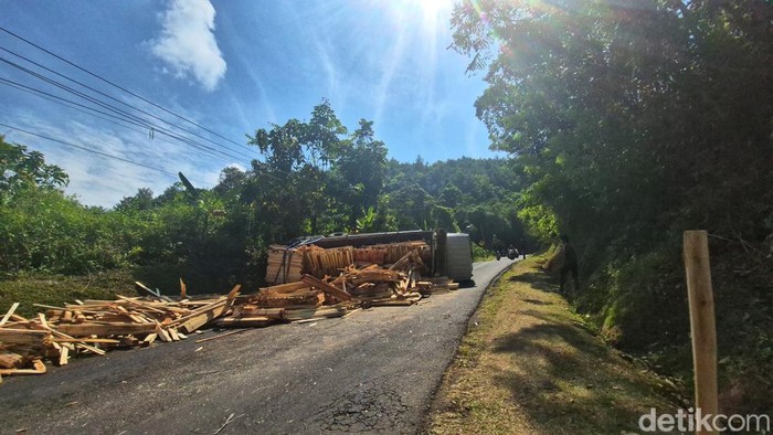 Sebuah truk bermuatan kayu bahan palet terguling di Tanjakan Pasir Bilik, Desa Buniwangi, Kecamatan Palabuhanratu, Kabupaten Sukabumi, Senin (8/9/2025). Muatan kayu berserakan di badan jalan dan membuat akses sempat tersendat
