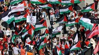 Seorang pengunjuk rasa mengibarkan bendera Palestina selama demonstrasi Garis Merah untuk Gaza, memprotes kondisi di Gaza dan menuntut pemerintah Belgia menjatuhkan sanksi terhadap Israel, di Brussels, Belgia, Minggu (7/9/2025). REUTERS/Yves Herman