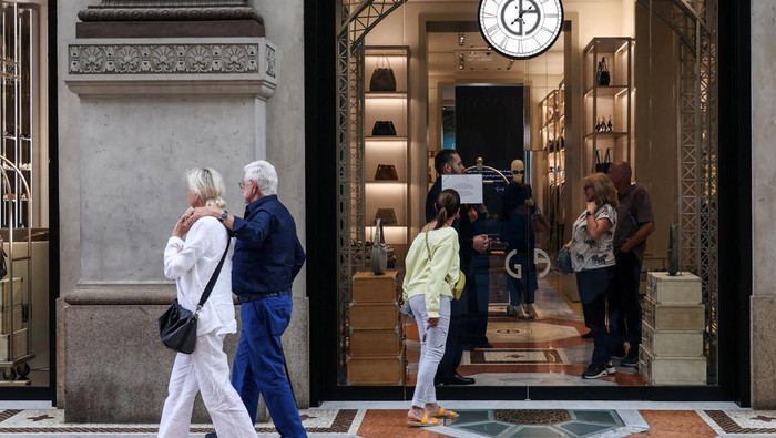 A person reads an announcement that says the closure of the shop for mourning on the day of the Italian fashion designer Giorgio Armani's funeral, at a Giorgio Armani store on Galleria Vittorio Emanuele II, in Milan, Italy September 8, 2025. REUTERS/Claudia Greco REFILE - CORRECTING CITY FROM 