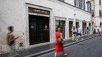 Orang-orang berjalan melewati toko Giorgio Armani yang tutup saat tutup untuk berkabung pada hari pemakaman perancang busana Italia tersebut, di Roma, Italia. REUTERS/Guglielmo Mangiapane