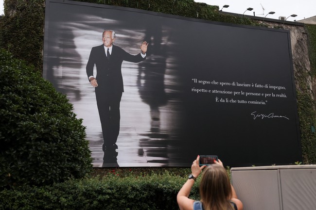 A person takes a photo of a billboard with an image of Italian fashion designer Giorgio Armani on the day of his funeral, in Milan, Italy September 8, 2025. REUTERS/Claudia Greco