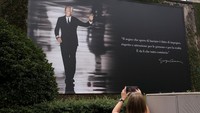 Seseorang mengambil foto papan reklame bergambar perancang busana Italia Giorgio Armani pada hari pemakamannya, di Milan, Italia. Armani meninggal dunia setelah lima dekade berkarier di mana ia membangun kerajaan bisnis yang mencakup haute couture hingga perabot rumah tangga, dengan namanya menjadi identik dengan kesederhanaan yang elegan. REUTERS/Claudia Greco