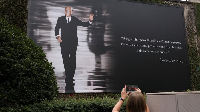 A person takes a photo of a billboard with an image of Italian fashion designer Giorgio Armani on the day of his funeral, in Milan, Italy September 8, 2025. REUTERS/Claudia Greco