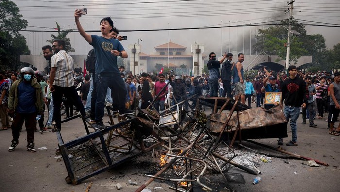 Demonstrators gather as smoke rises from the Parliament complex following fire set during a protest against Mondays killing of 19 people after anti-corruption protests that were triggered by a social media ban, which was later lifted, during a curfew in Kathmandu, Nepal, September 9, 2025. REUTERS/Adnan Abidi            TPX IMAGES OF THE DAY