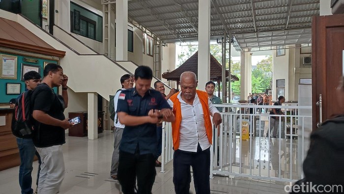 I Wayan Wendita dipapah petugas seusai menjalani sidang kasus jual-beli penyu hijau di PN Denpasar, Selasa (9/9/2025). (Foto: Ahmad Firizqi Irwan/detikBali)