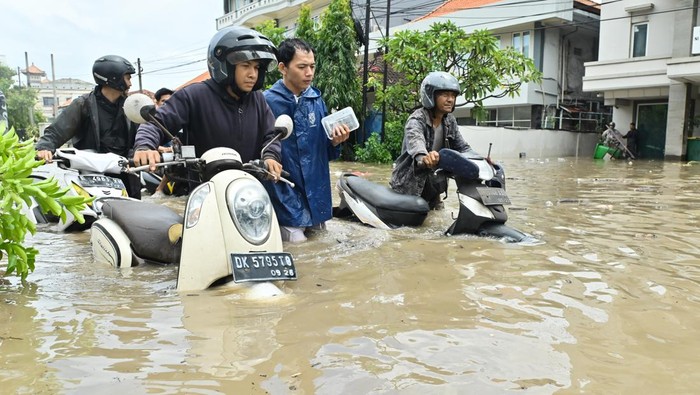 Warga mendorong sepeda motor melewati banjir yang menggenangi kawasan Kuta, Badung, Bali, Rabu (10/9/2025). Hujan yang mengguyur wilayah Bali sejak Selasa (9/9) mengakibatkan banjir di berbagai titik dengan ketinggian air yang bervariasi hingga mencapai 1,5 meter. ANTARA FOTO/Fikri Yusuf/nym.