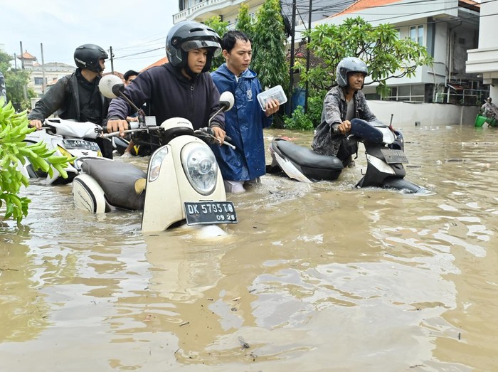 Warga mendorong sepeda motor melewati banjir yang menggenangi kawasan Kuta, Badung, Bali, Rabu (10/9/2025). Hujan yang mengguyur wilayah Bali sejak Selasa (9/9) mengakibatkan banjir di berbagai titik dengan ketinggian air yang bervariasi hingga mencapai 1,5 meter. ANTARA FOTO/Fikri Yusuf/nym.