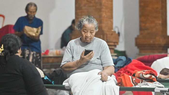 Warga menghubungi keluarganya di posko pengungsian bencana banjir di kawasan Denpasar Timur, Denpasar, Bali, Rabu (10/9/2025). Sekitar 80 orang warga di kawasan tersebut mengungsi di dua titik pengungsian akibat tempat tinggalnya rusak diterjang banjir. ANTARA FOTO/Fikri Yusuf/nz