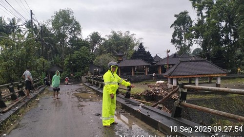 Kondisi jalan penghubung Desa Sudimara dengan Desa Bengkel, Tabanan, lumpuh akibat air Sungai Yeh Ho meluap membawa material kayu. (Istimewa)