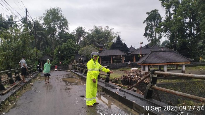 Kondisi jalan penghubung Desa Sudimara dengan Desa Bengkel, Tabanan, lumpuh akibat air Sungai Yeh Ho meluap membawa material kayu. (Istimewa)