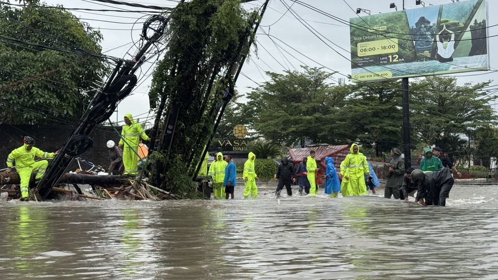 Petugas dan warga bergotong royong memindahkan halte bus dan tiang kabel komunikasi yang roboh dan menghalangi jalan di depan Mako Brimob Polda Bali, Selasa (10/9/2025). (Dok. DetikBali/I Nyoman Adhisthaya Sawitra)