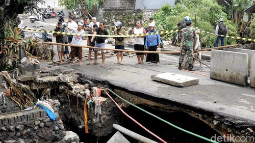 Petugas memasang garis larangan melintas di lokasi jalan amblas dekat Pasar Pengosari, Kerobokan, Kuta Utara, Rabu (10/9/2025). (Agus Eka/detikBali)