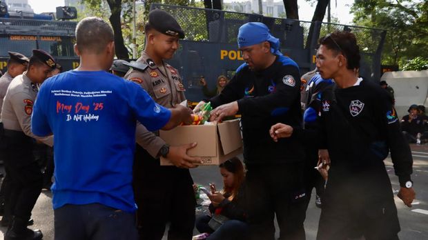 Polisi membagikan air mineral dan roti kepada massa buruh yang demo di Monas, Jakpus, Rabu (10/9/2025).