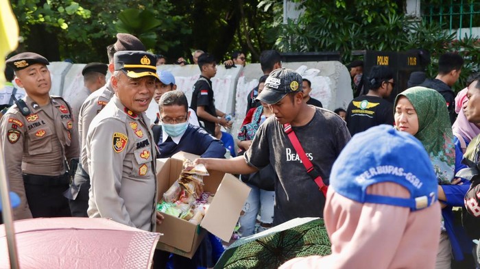Polisi membagikan air mineral dan roti kepada massa buruh yang demo di Monas, Jakpus, Rabu (10/9/2025).