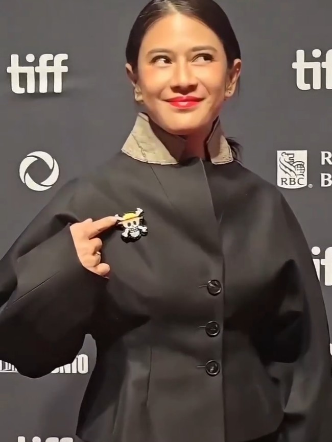 Saat berpose di depan kamera, aktris yang memilih tatanan rambut minimalis dengan gaya kuncir kuda ini terlihat berpose menunjuk pin yang dikenakannya. Foto: Instagram/@theraldisastr @greenlightpictures