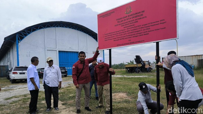 Kejagung, Kejati Papua dan Kejari Gresik memasang papan penyitaan di salah satu aset tanah di Wringinanom, Gresik