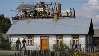 Petugas polisi berjaga di depan rumah yang atapnya rusak akibat puing drone di Wyryki, Polandia tenggara, Rabu (10/9/2025). Foto: REUTERS/Kacper Pempel