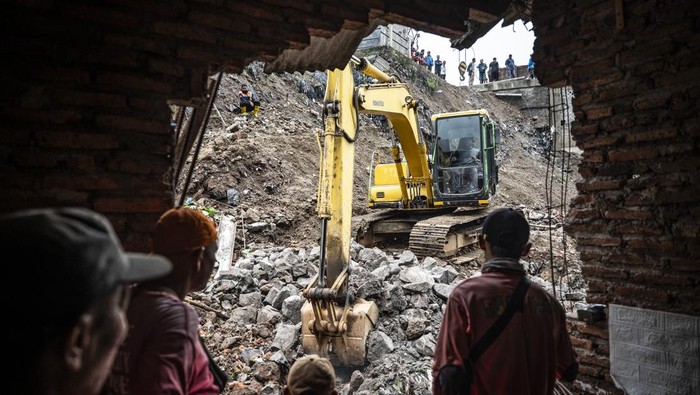 Petugas menggunakan alat berat memindahkan material longsor di Karanganyar Gunung, Candisari, Semarang, Jawa Tengah, Kamis (11/9/2025). Badan Penanggulangan Bencana Daerah (BPBD) Kota Semarang menyebutkan bahwa tanggul setinggi 15 meter dan sepanjang 150 menter itu longsor akibat pondasi lama yang tidak lagi mampu menahan beban setelah diguyur hujan deras pada Rabu (11/9) serta menyebabkan satu rumah mengalami kerusakan dan banjir di kawasan tersebut. ANTARA FOTO/Aprillio Akbar
