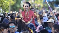 Senyuman seorang wanita berbusana adat di atas kuda, menjadi pusat perhatian dalam perayaan. Foto: Kholik
