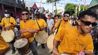 Kelompok penabuh genderang dalam busana kuning cerah memimpin suasana meriah festival.