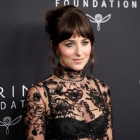 Dakota memilih riasan wajah minimalis bernuansa nude dengan fokus pada eyeshadow bergaya smokey. Rambut brunette-nya disanggul tinggi, menyisakan poni dan beberapa helaian rambut yang membingkai wajah. Foto: Getty Images/Mike Coppola