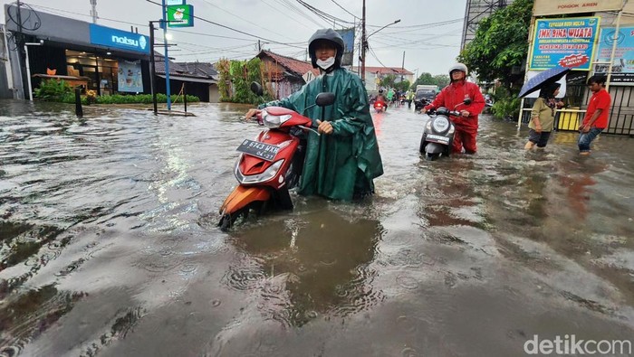 Para pengendara melintas di genangan air yang merendam Jalan Pondok Aren Raya, Tangerang Selatan, Banten, Jumat (12/9/2025).