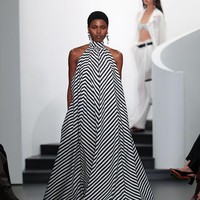 Warna utama untuk jaket dan mantel adalah putih bersih, seperti pada busana pertama: mantel polo putih panjang yang terbuka memperlihatkan bra hitam dipadukan dengan celana hitam. (Foto: Dia Dipasupil/Getty Images)