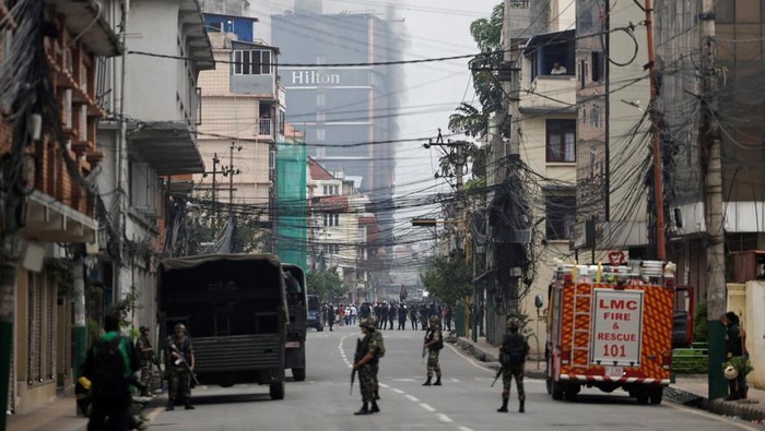 Nepali army soldiers stand guard as smoke rises from the Hilton hotel, following protests against Mondays killing of 19 people after anti-corruption protests triggered by a social media ban which was later lifted, in Kathmandu, Nepal, September 10, 2025. REUTERS/Navesh Chitrakar