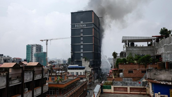 NEPAL-PROTESTS/ Hotel Hilton Nepali army soldiers stand guard as smoke rises from the Hilton hotel, following protests against Monday's killing of 19 people after anti-corruption protests triggered by a social media ban which was later lifted, in Kathmandu, Nepal, September 10, 2025. REUTERS/Navesh Chitrakar