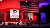 Seorang pria terlihat memegang bendera AS dengan penuh khidmat, sementara warga lain berdoa bersama mengenang sosok Kirk. Bagi para pendukungnya, Kirk dikenal vokal menyuarakan pandangan konservatif serta aktif menggerakkan generasi muda dalam politik sayap kanan. REUTERS/Jim Urquhart