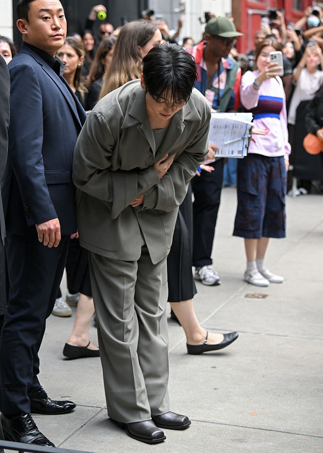 Begitu turun dari mobil, Jungkook BTS disambut kerumunan penggemar yang telah menunggu kedatangannya. Ia tampak membungkuk dan menundukkan kepala sebagai sapaan. Foto: Getty Images