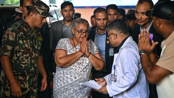 Newly-elected Prime Minister of Nepals interim government Sushila Karki (C) is greeted by a medical personnel as she arrives at the National Trauma Center hospital to visit victims injured in clashes with security personnel, in Kathmandu on September 13, 2025. Nepals capital on September 13, took a step back towards normality after deadly anti-corruption protests, as daily life returned with a curfew eased and an interim prime minister sworn into office. (Photo by Arun SANKAR / AFP)