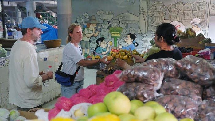Pedagang melayani wisatawan mancanegara saat berbelanja di Pasar Badung, Denpasar, Bali, Minggu (14/9/2025). Menurut pihak Perumda Pasar Sewakadarma Kota Denpasar, sebagian pedagang di lantai satu hingga empat di pasar itu sudah kembali berjualan dan situasi mulai normal usai pemadaman listrik akibat bencana banjir di area parkir bawah tanah di pasar tersebut pada Rabu (10/9). ANTARA FOTO/Nyoman Hendra Wibowo/bar