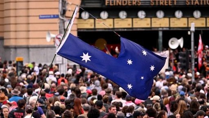 People hold up placards during an anti-racism protest march in Melbourne on September 13, 2025 to counter anti-immigration and anti-government protesters from a Save Australia rally. (Photo by William WEST / AFP)