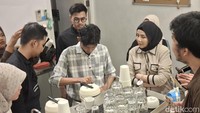 Rizky dan Rival memastikan seluruh peserta melakukan prosedur dengan baik. Terlihat ketika Rival menawarkan bantuan untuk menggambar latte art dengan membimbing tangan peserta. Foto: Diah Afrilian/detikcom