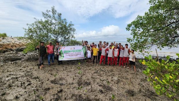Polisi dan siswa SD menanam mangrove di pinggir pantai di Dumai.